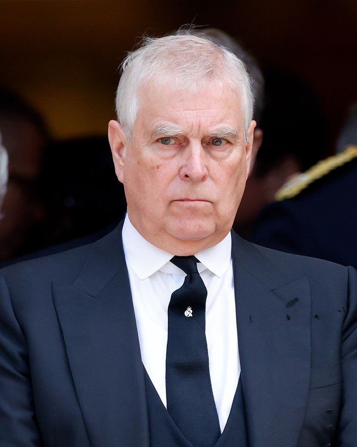 Older man in a dark suit and black tie with a serious expression amid exotic dancer shocking allegations keywords.