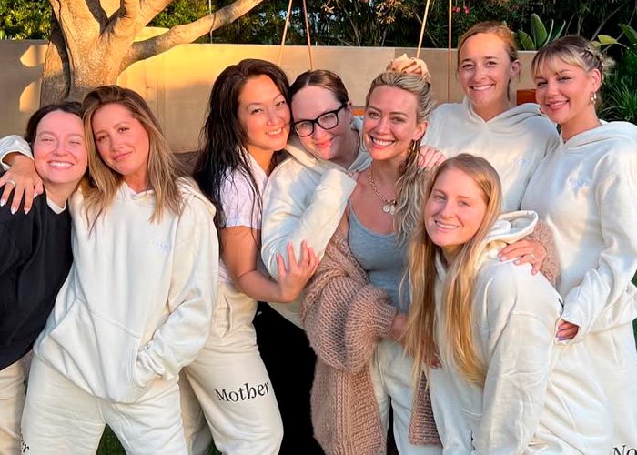 Group of women outdoors smiling and posing together, highlighting drama involving Kaley Cuoco and Ashley Tisdale toxic mom topic.