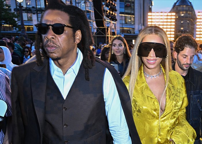 Jay-Z and Beyoncé wearing sunglasses at an outdoor event, highlighting Blue Ivy's resemblance to her mom.