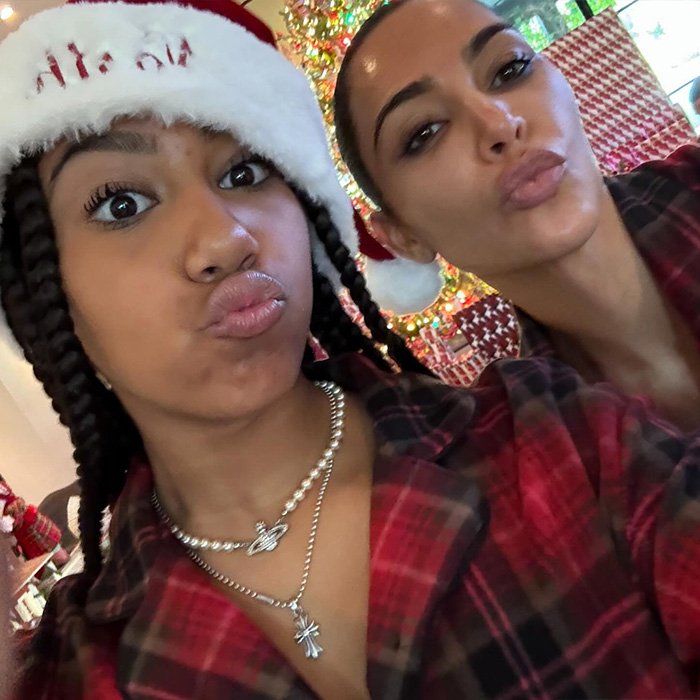 North West and Kim Kardashian posing for a selfie with a Christmas tree in the background, showing recent piercings.