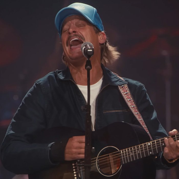 Male musician passionately singing and playing guitar during Turning Point USA alternate halftime show performance.