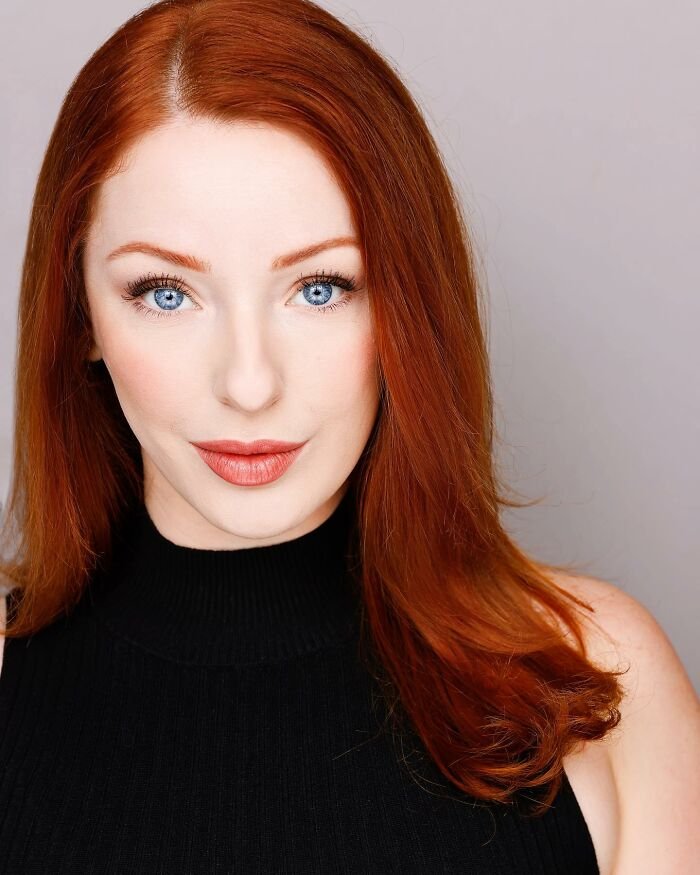 Red-haired woman with blue eyes in a black top, representing ex-Disneyland Evil Queen sharing truth behind controversial firing.