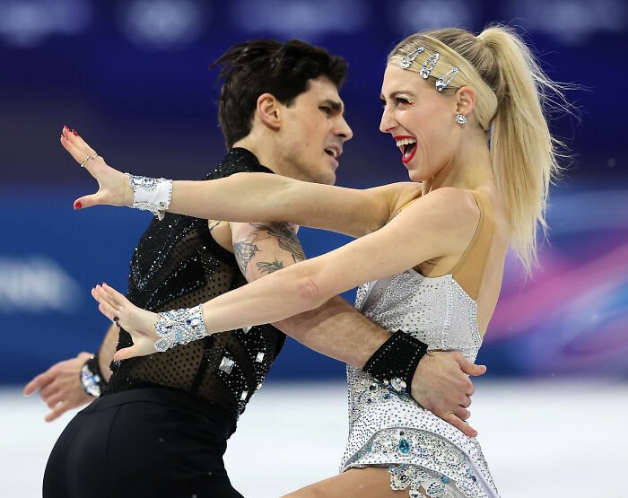 Olympic ice skater and partner performing a dynamic routine on ice rink, showcasing skill and grace during competition.