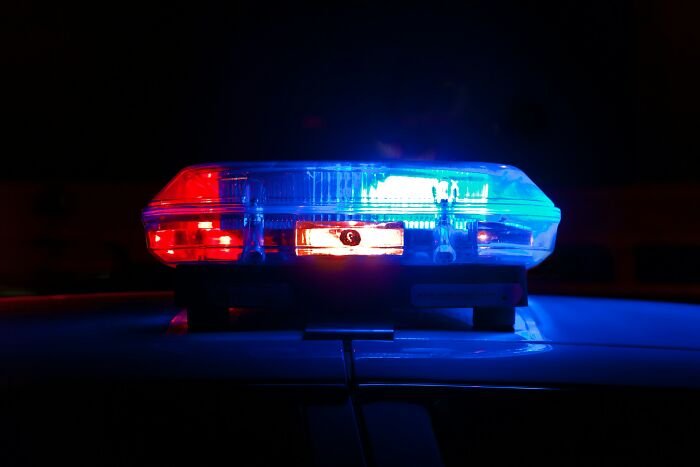 Police car light bar flashing red and blue at night related to missing woman case, 24, located after final call.