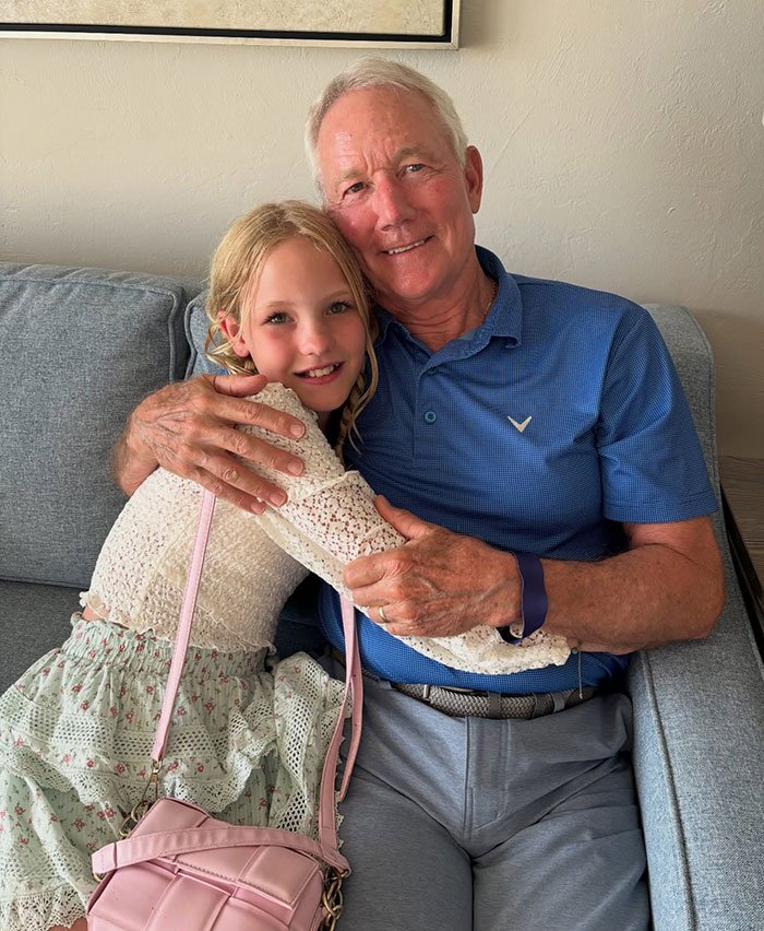 Elderly man and young girl hugging on a couch, reflecting on James Van Der Beek’s final post breaking hearts.