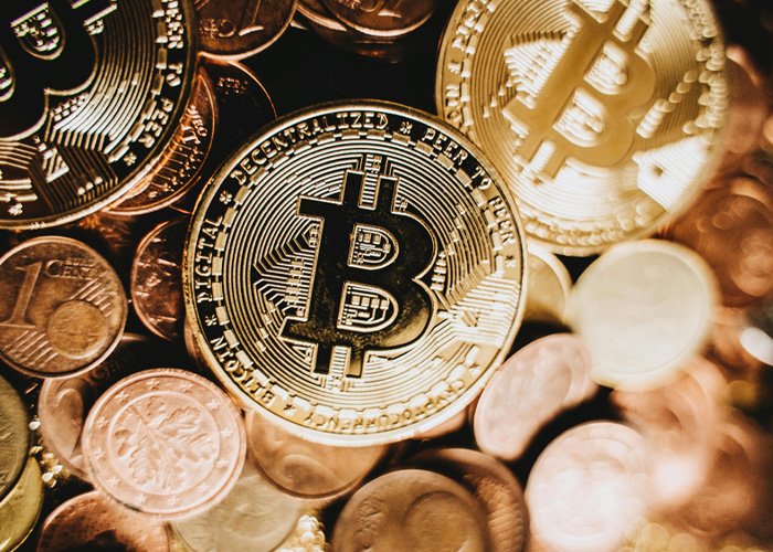 Close-up of physical Bitcoin coins stacked among various other coins, symbolizing cryptocurrency and exchange control.