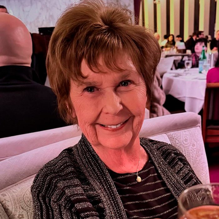 Older woman smiling in a restaurant setting, related to crypto expert explaining bitcoin exchange police control case.