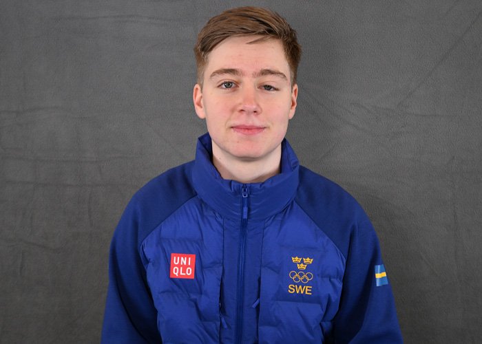 Young Swedish Olympian wearing blue jacket with Olympic and Swedish flag logos amid misgendering incident debate.