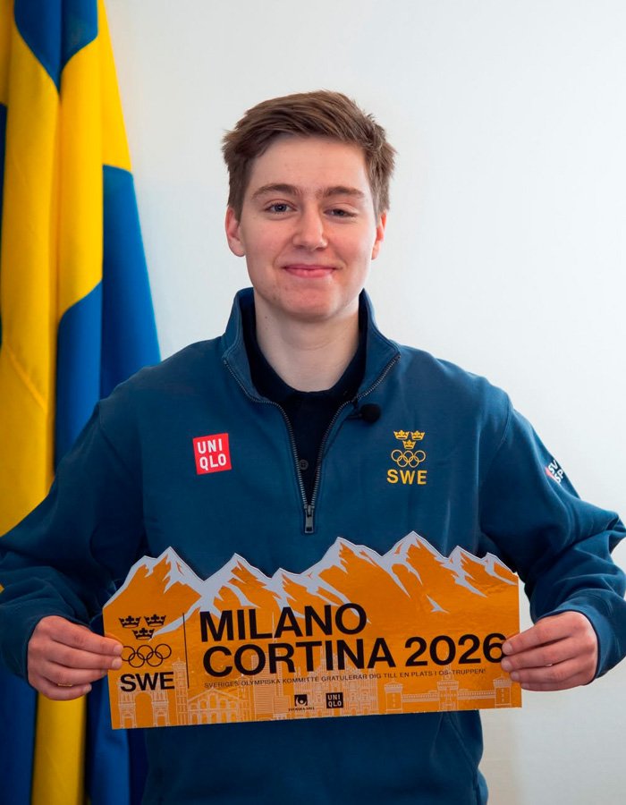 Trans Olympian in Sweden team jacket holding Milano Cortina 2026 sign amid misgendering incident debate.