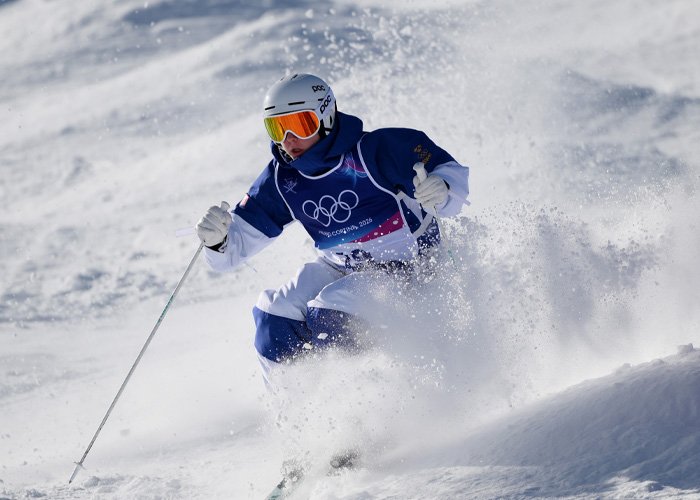 Trans Olympian skiing at the Olympics, captured mid-action amid a snowy slope during a competitive event.