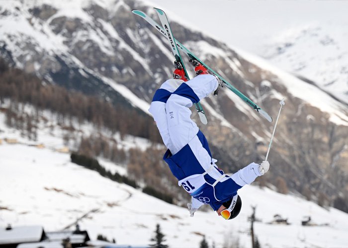 Olympian performing a midair ski flip during winter competition amid heated debate on misgendering incident.