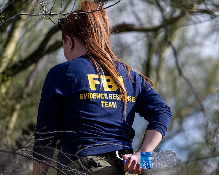 FBI evidence response team member outdoors near white tent set up days after kidnapping investigation at Nancy Guthrie's home