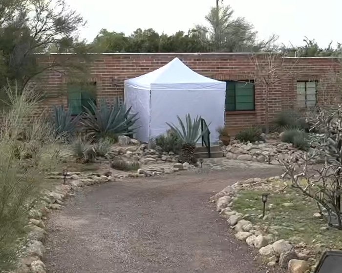 White forensic tent set up at Nancy Guthrie home days after kidnapping near brick house and garden path.