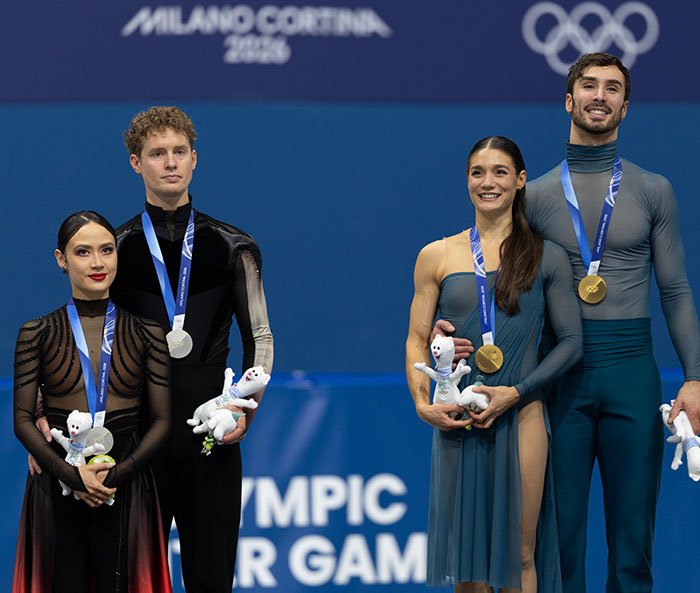 Two pairs of figure skaters wearing medals during the Olympics ceremony, with focus on French skater and suspicious win.