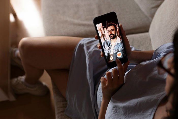 Woman on couch using dating app, illustrating former FBI agent safety tips for women to consider online interactions.