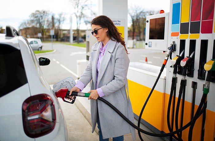 Woman at gas station wearing sunglasses and coat, illustrating former FBI agent safety tips for women in everyday situations.