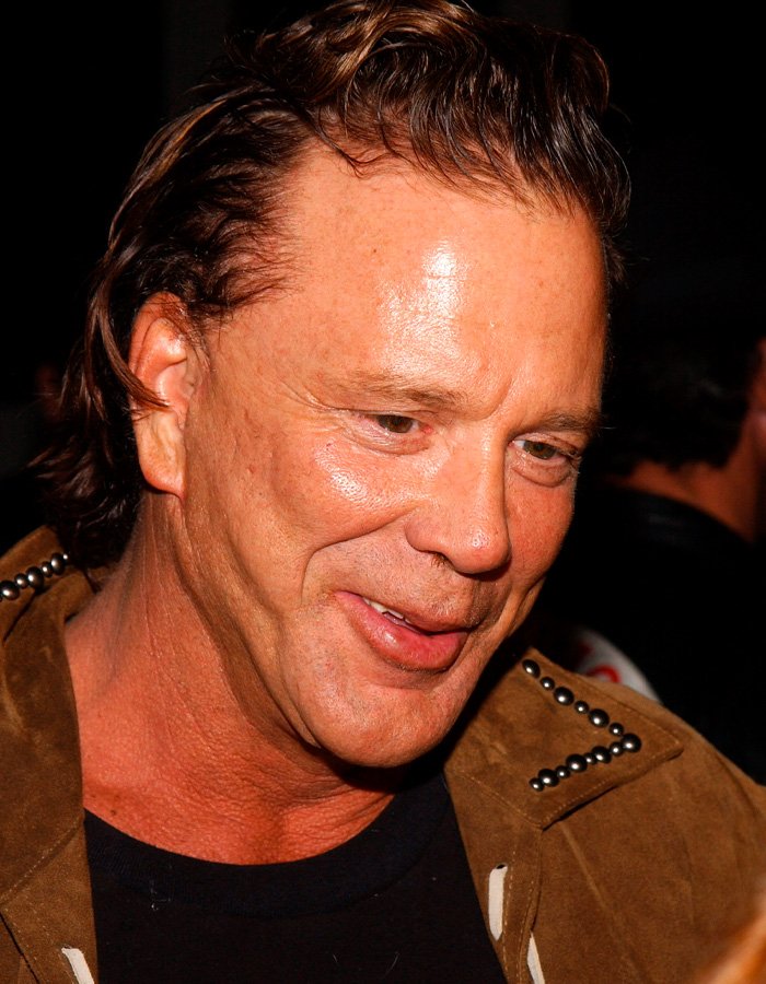 Mickey Rourke smiling at an event showing his natural look without dramatic cosmetic procedures.