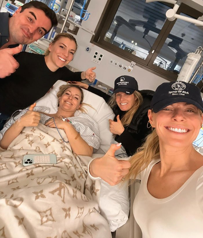 Lindsey Vonn in hospital bed surrounded by friends giving thumbs up after horrific Olympics accident update.