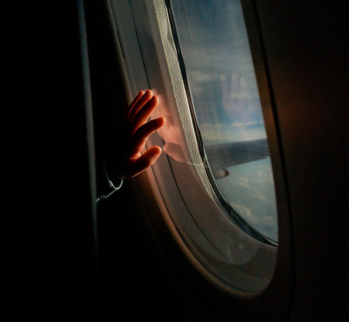 Toddler’s hand touching airplane window, illustrating Southwest seating dispute over refusing to pay extra.