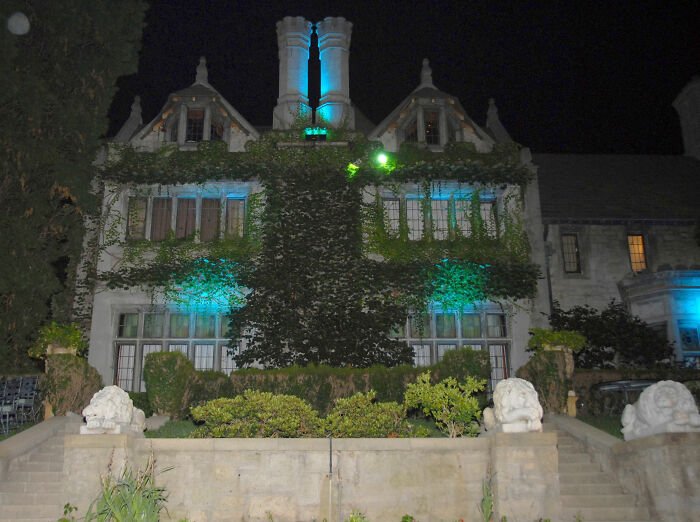 Large mansion covered in ivy with blue lighting at night, related to Playboy founder and Hugh Hefner's widow claim.