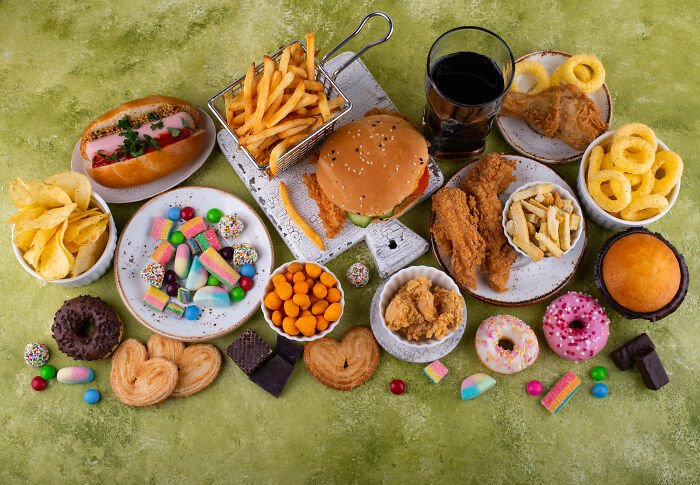 Assortment of fried foods, sugary snacks, and soda highlighting diet risks related to colon cancer breakthrough research.