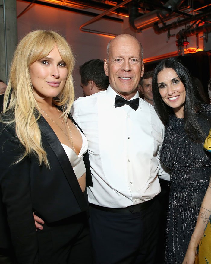 Rumer Willis posing with Bruce Willis and Demi Moore at an event, highlighting her work life despite famous parents.