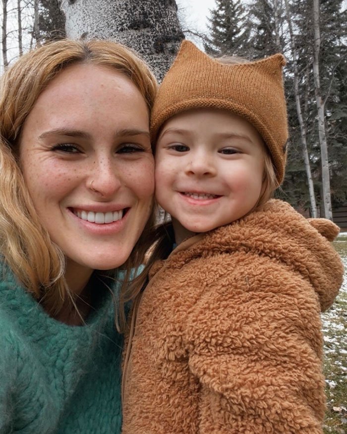 Rumer Willis smiling outdoors with a child, highlighting her need to work four jobs despite famous parents Bruce Willis and Demi Moore.