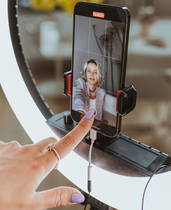 Woman recording video on smartphone with ring light, exploring suspicions about late brother’s baby and family drama.