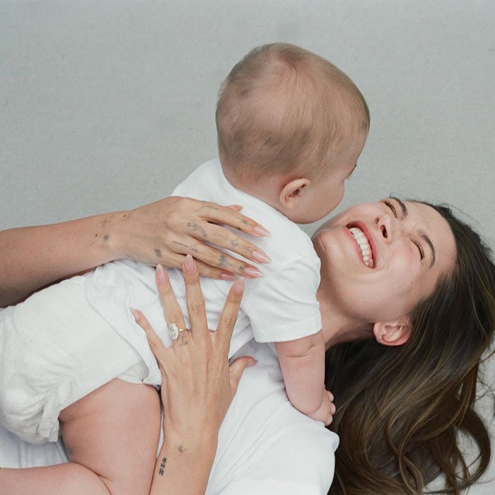 Hailey Bieber smiling while holding her toddler son, highlighting a pathological liar claim met with public skepticism.