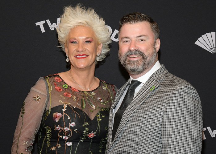Anne Burrell with a man at an event, posing in front of a black backdrop, related to police report on tragic passing details.