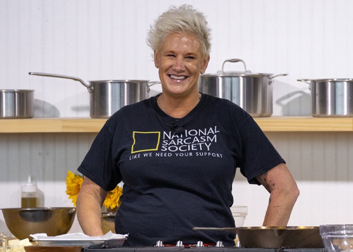 Chef Anne Burrell smiling in a kitchen setting with pots and pans, related to police report alleged tragic passing.