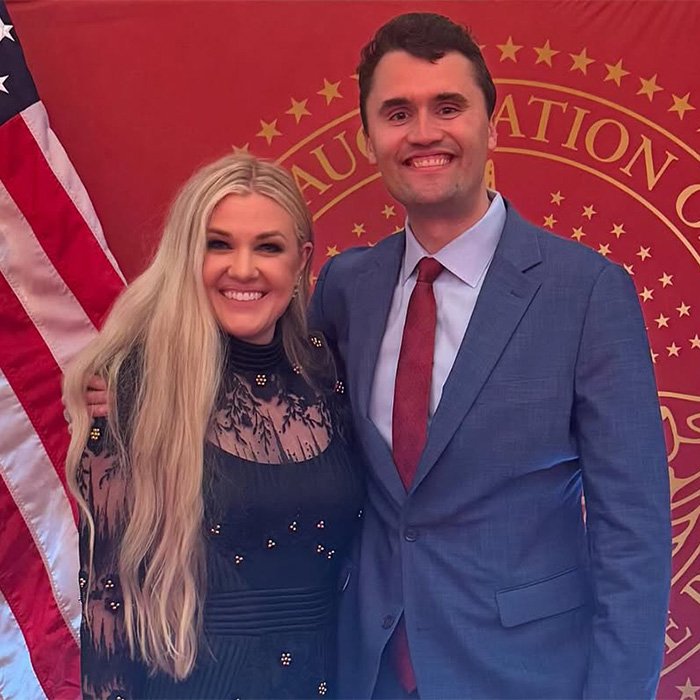 Two people smiling and posing closely together at a formal event with a red backdrop and American flag, hinting at closet lesbian rumors.