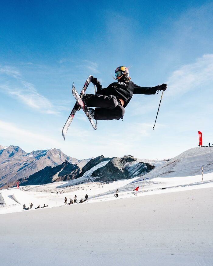 Skier performing a high jump in snowy mountains, highlighting Eileen Gu’s athletic skills and winter sports representation.
