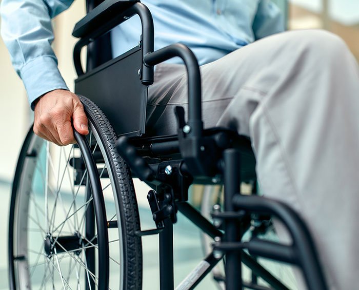 Person seated in wheelchair gripping the wheel, illustrating commonly ignored ALS symptoms and mobility challenges.