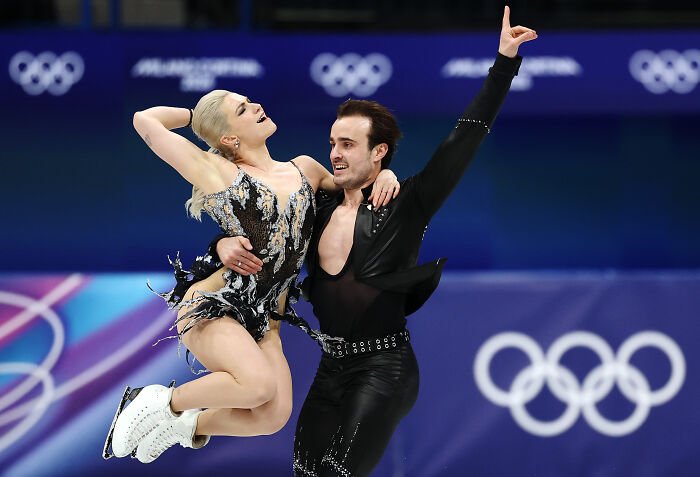 Figure skating pair performing during Winter Olympics event with host facing pressure after commentary sparked outrage.