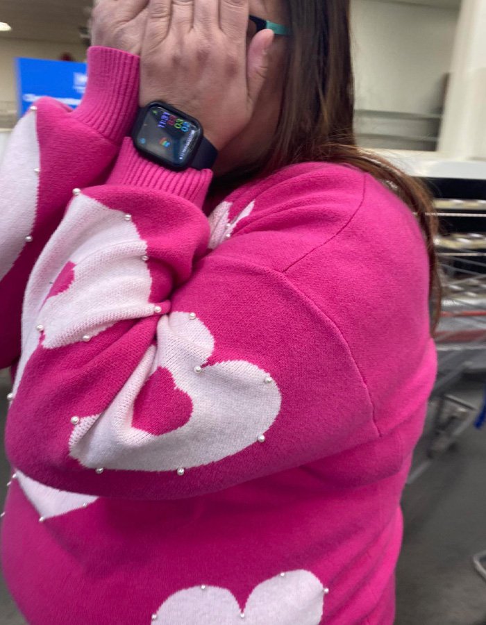 Woman in a pink sweater covering her face, related to teacher jailed over alleged racist attack incident.