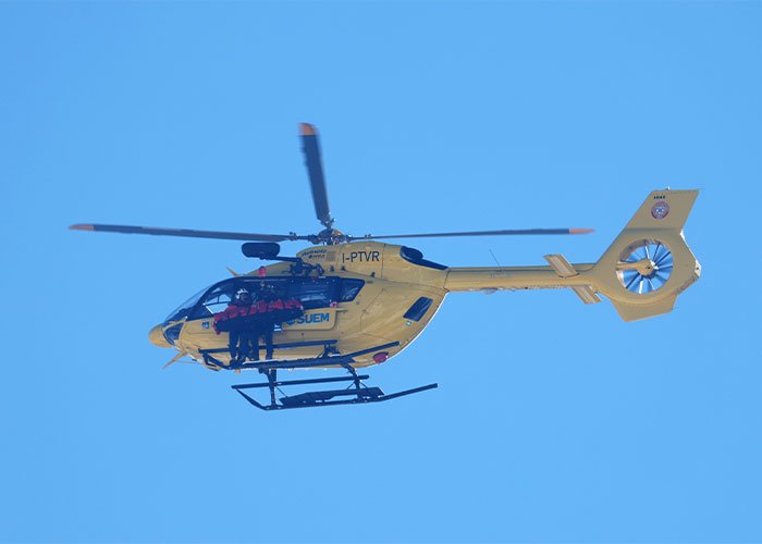 Yellow medical helicopter flying with rescue team on board during emergency response following Lindsey Vonn's broken leg surgery.