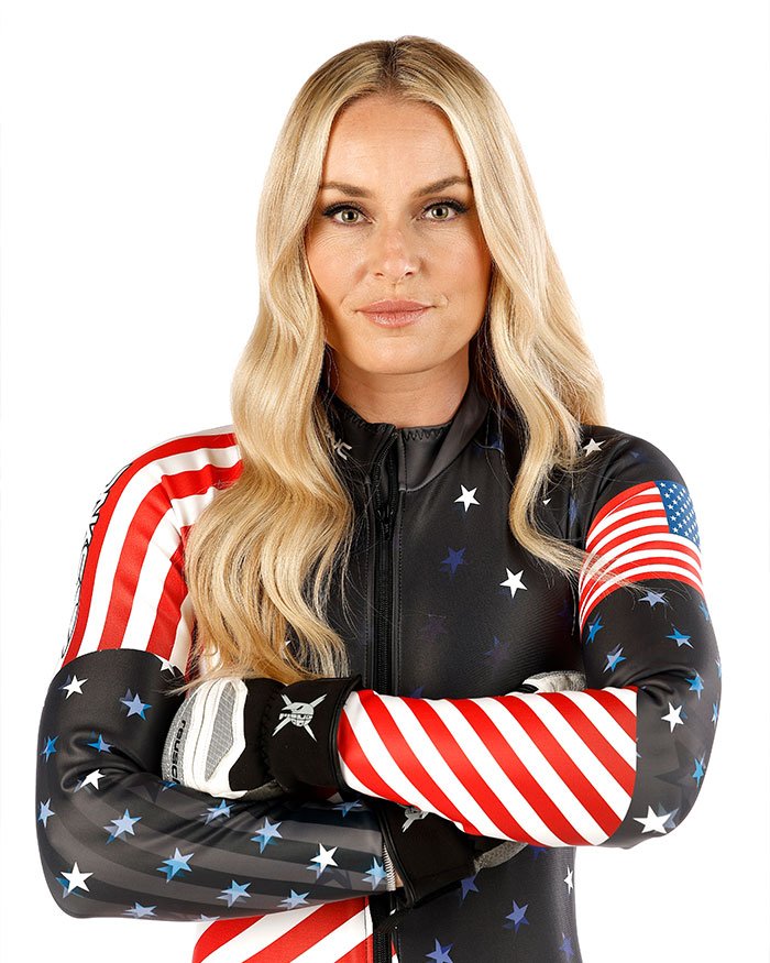 Lindsey Vonn in USA-themed ski suit with crossed arms following fifth surgery on broken leg recovery update.