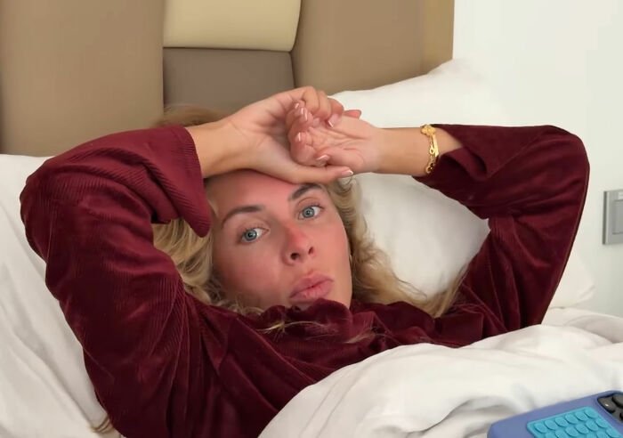 Woman lying in bed wearing a maroon top, appearing surprised, related to Bonnie Blue pregnancy challenge news.