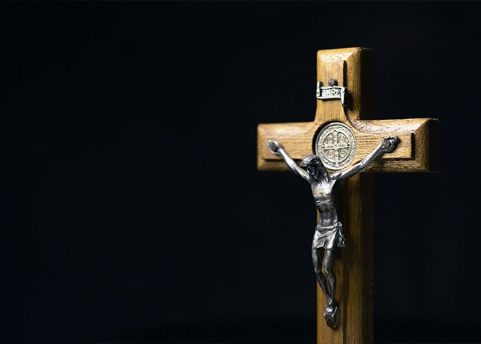 Wooden crucifix with metal Jesus figure on dark background related to Elon Musk's Jesus comment theories.