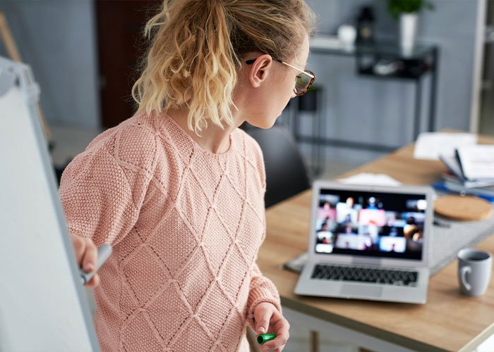 Teacher in pink sweater conducting an online class on laptop, highlighting a shocking hot-mic moment that stunned students.