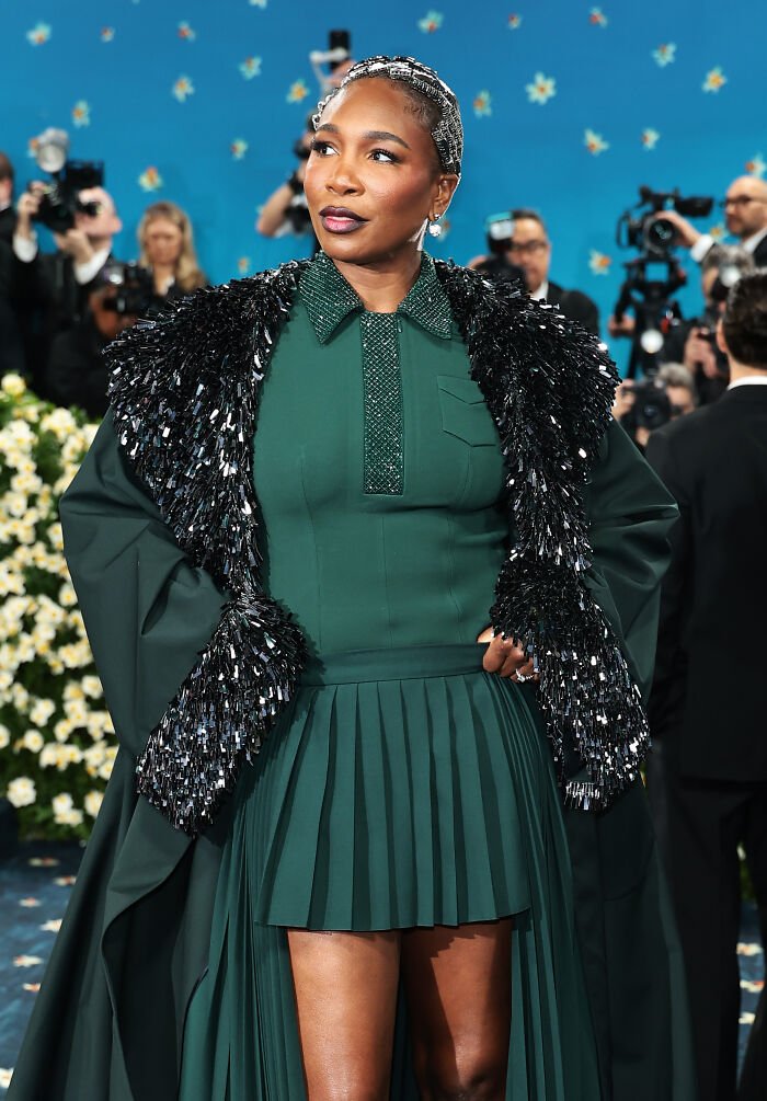 Woman wearing a green dress with black sequined cape at an event, highlighting Met Gala 2026 dress code controversy.