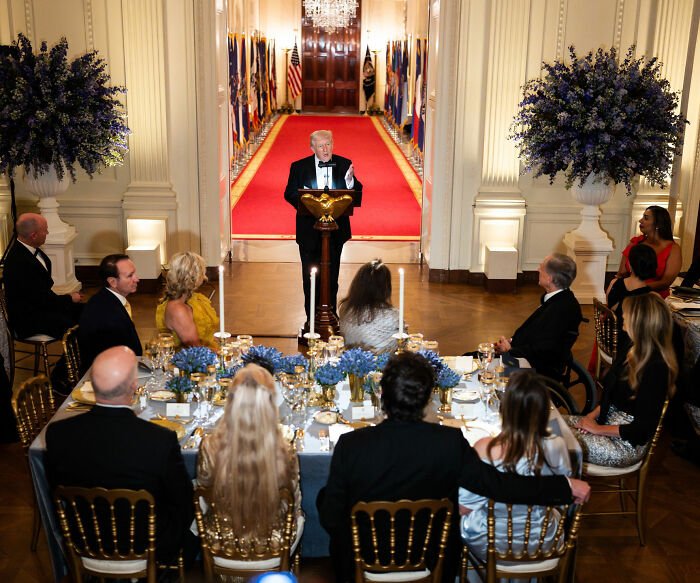 Donald Trump speaking at a formal dinner with attendees seated, highlighting Melania Trump’s governors dinner outfit controversy.