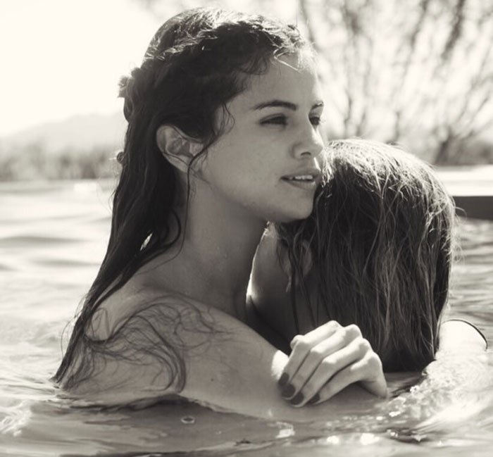 Selena Gomez in a swimsuit embracing another person in a pool, sparking a heated debate after fans notice odd detail.