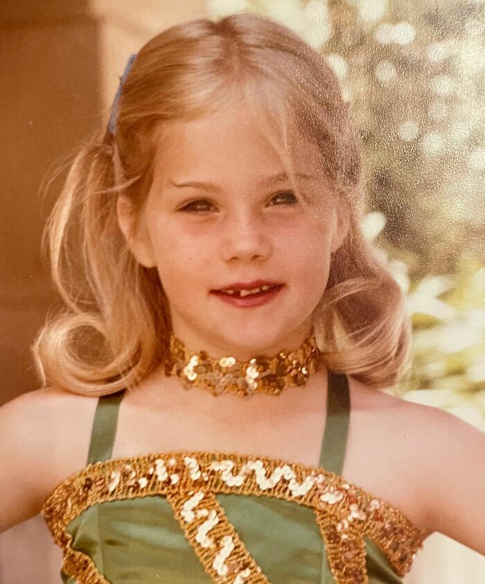 Young girl dressed in a green and gold costume, smiling softly, representing Christina Applegate and multiple sclerosis awareness.