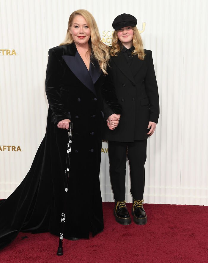 Christina Applegate holding a cane and hand of a young person at a formal event, relating to multiple sclerosis update.