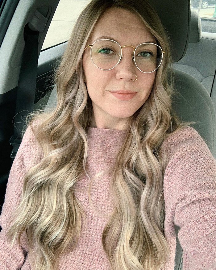 Woman with long blonde hair and glasses sitting in car, feeling concerned after discovering boyfriend’s YouTube history and danger signs.