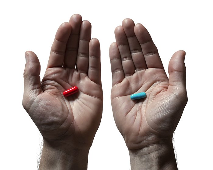 Pair of hands holding a red and a blue pill, symbolizing choice and danger in a tense situation.