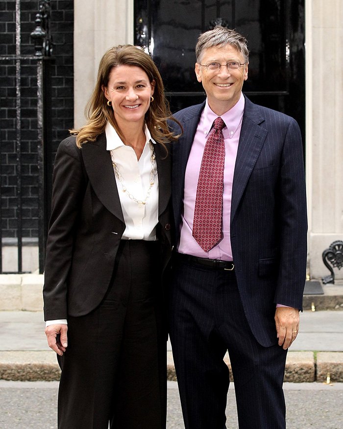 Bill Gates standing with a woman outdoors, both dressed formally amid Epstein scandal and apology discussions.