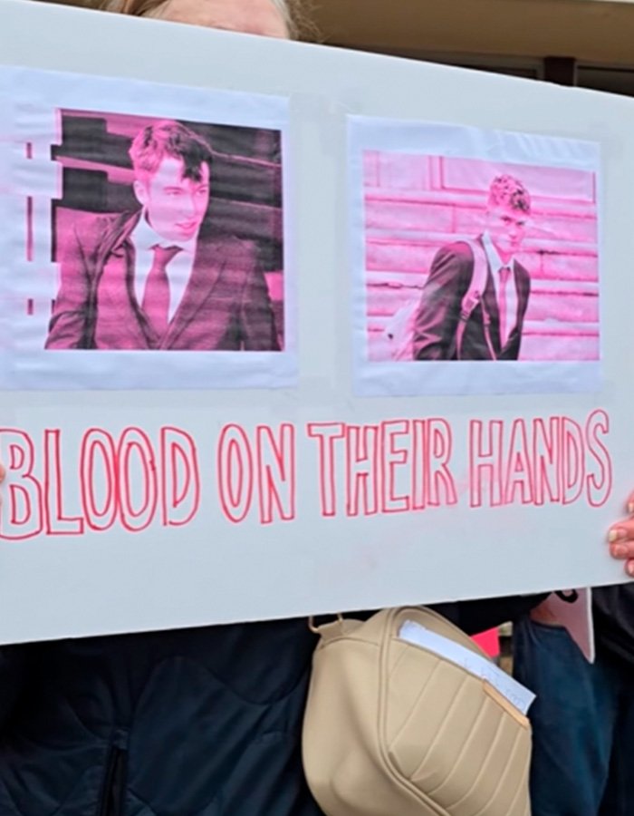 Protest sign with images of two students referring to karma and their fate after blowing up sheep with fireworks.